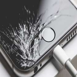 A cracked smartphone screen with visible shattered glass and black lines across the display